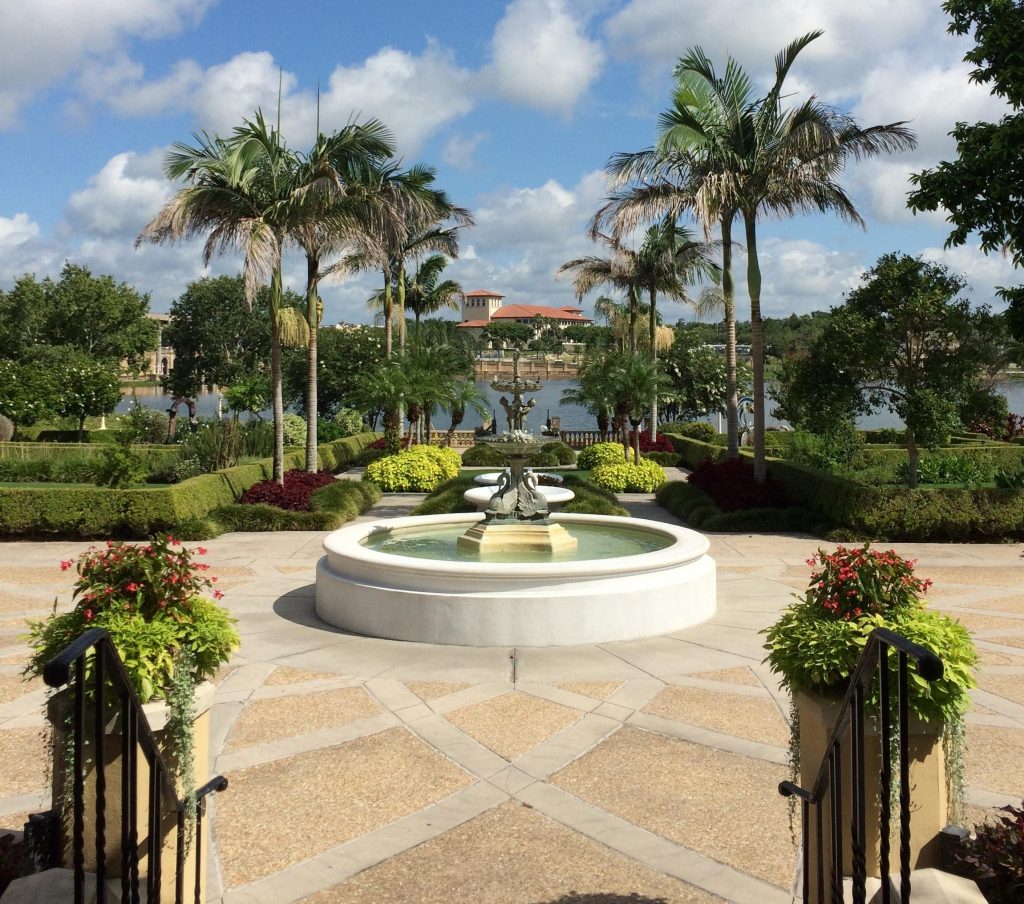 Scenic shot of a water fountain, palm trees, and a lake. Credit: The Ledger